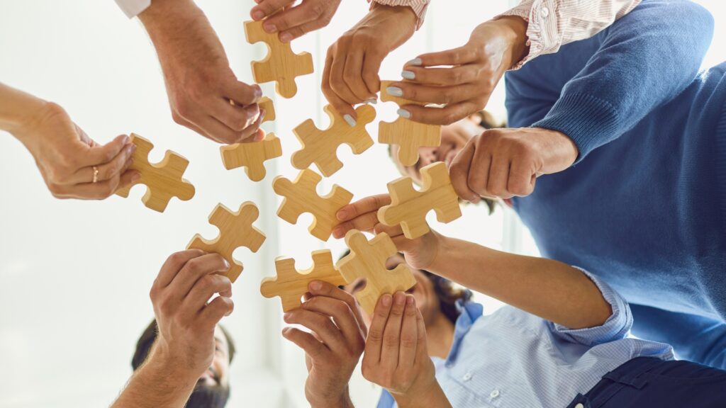 Multiple hands holding puzzle pieces